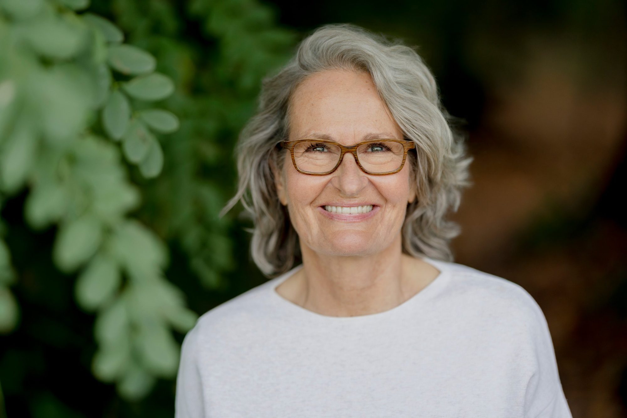 Porträt von Birgit-Rita Reifferscheidt, lächelnd vor grünen Blättern